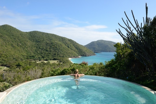 A woman gazes over the landscape of Guana Island from the resort's swimming pool