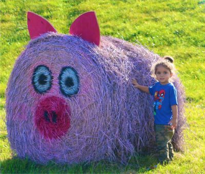 A girl with a decorated hay bale at Heaven Hill Farm