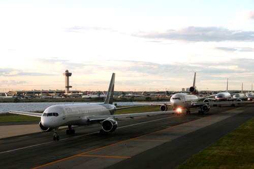 A long line of planes queued on the tarmac, awaiting takeoff at JFK International Airport.
