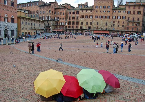 The most beautiful piazza in Italy is dramatically shaped like a sloping scallop shell or fan, divided into nine sections in honor of the Council of Nine, who ruled Siena during its golden age, and graced with a copy of the original Fonte Gaia (Fountain of Joy), created by the city's own Jacopo della Quercia.<br><br><em>Photo Caption: The Campo in Siena, Italy on a drizzly March morning.</em>