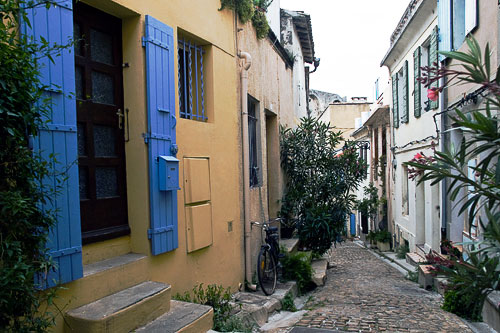 A colorful building and view of a narrow street in Arles