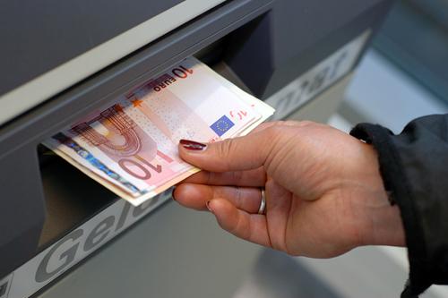 A woman receives european money at an atm in germany.