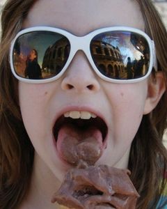 As the author’s 10-year-old daughter licks her gelato, reflected in her sunglasses are the Colosseum of Rome and the author, licking her own gelato