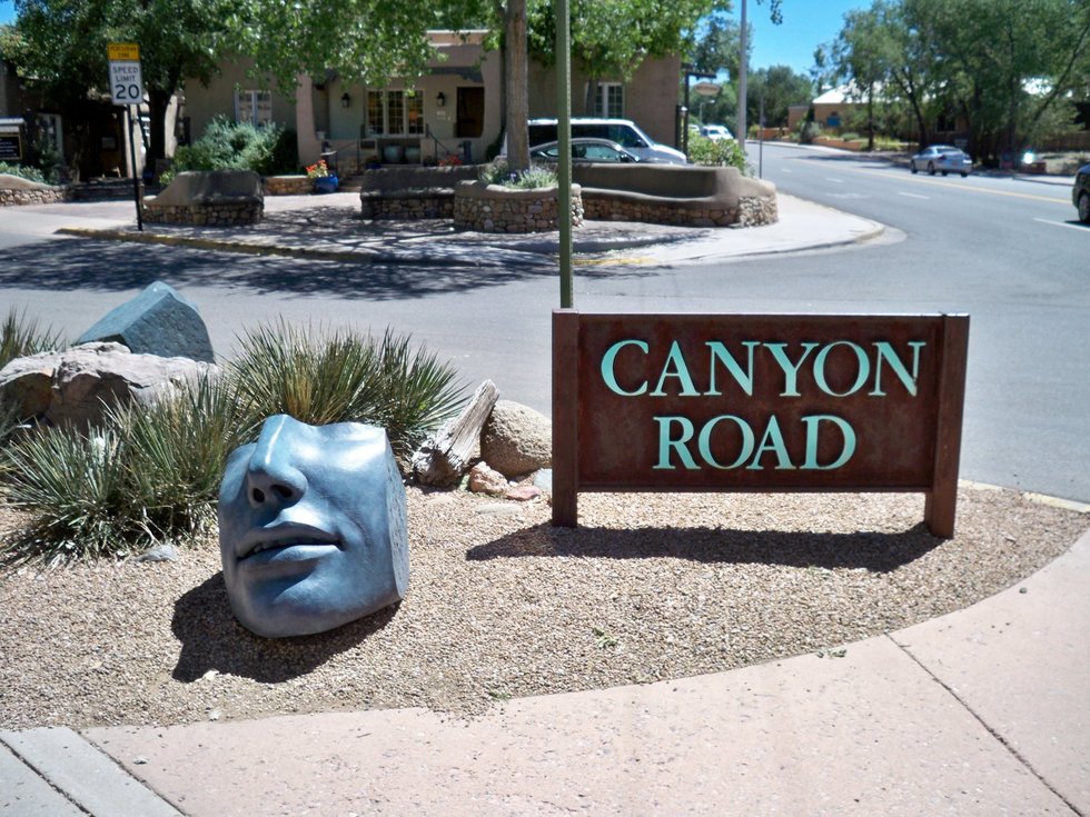 Bronze face fragments by Susan Stamm Evans welcome visitors to Canyon Road.