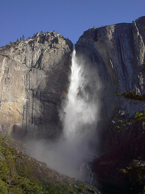 Yosemite Falls is shown, a tall waterfall in the fissure between two large rock formations.