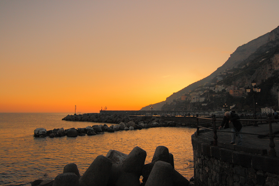 A silhouette of the Amalfi Coastline and an orange sunset. 