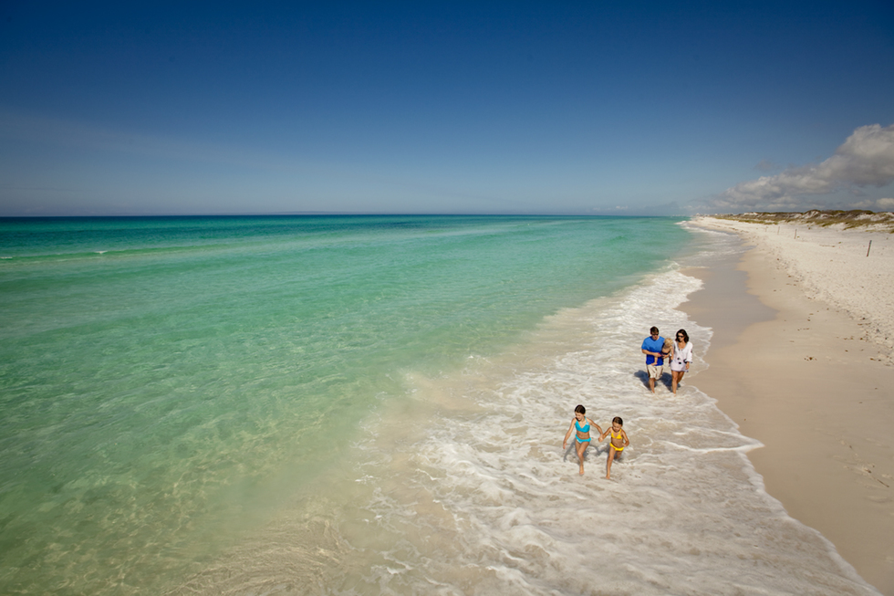 Crystal clear green and blue waters of the Florida ocean washing up onto white sand. 