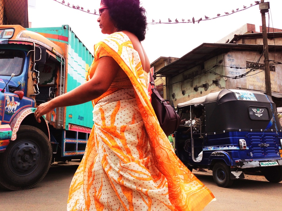 A Sri Lankan woman walks by colorful trucks