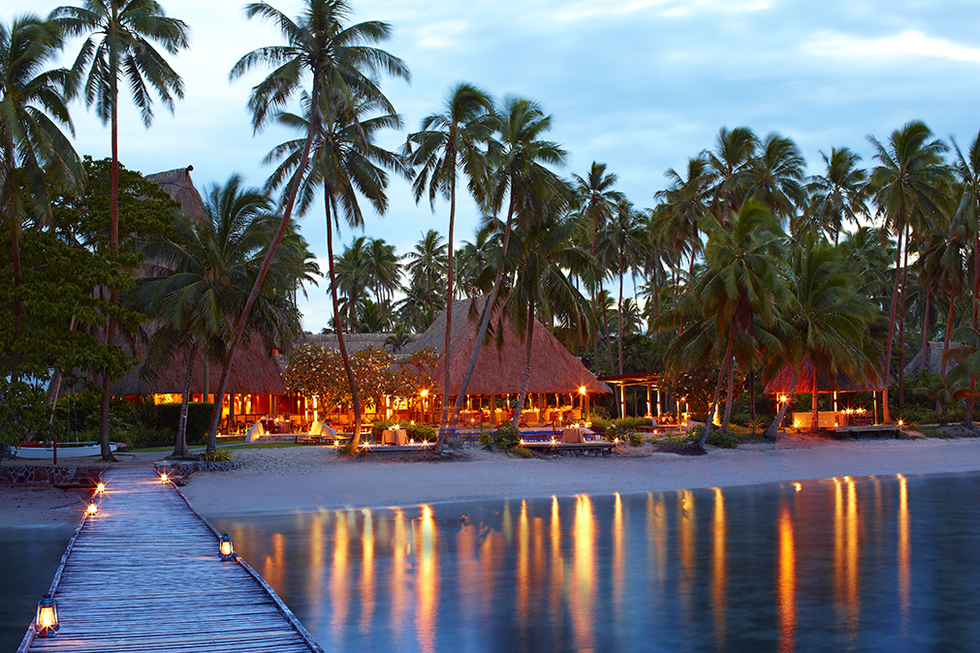 A view of the bungalows at night from the water. 