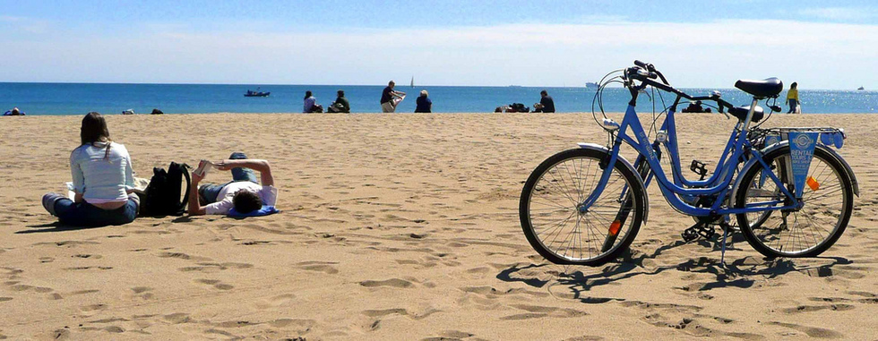 A couple takes a break in the sand after biking along Barcelona's beachfront