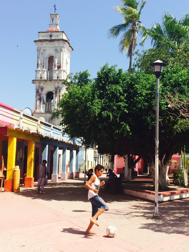 A boy plays soccer in the town square of Mexcaltitan
