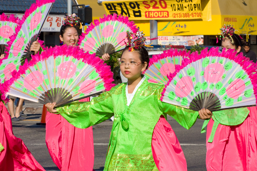 A girl dancing with traditional fans at the Korean Festival and Parade.