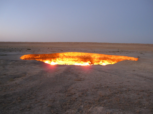 A large, fiery pit burning in the middle of the desert