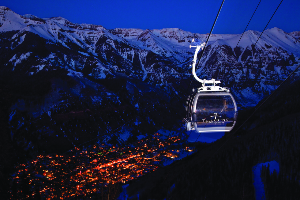A gondola slides down to a night-lit town of Telluride