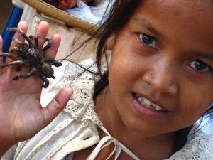 A girl holds a fried tarantula
