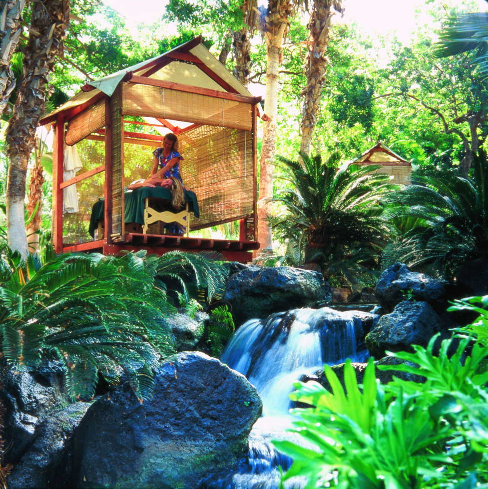A woman gets a massage in a hut over a waterfall at the Fairmont Orchid Resort.
