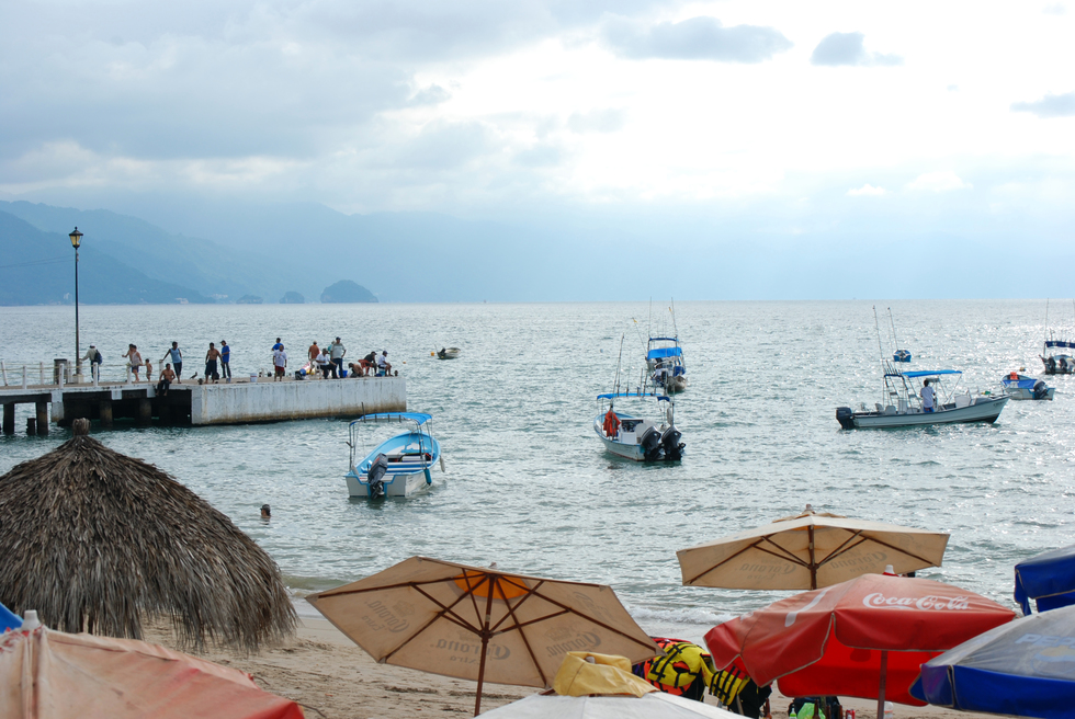 Umbrellas on the beach of Puerto Vallarta, sailboats in the sea