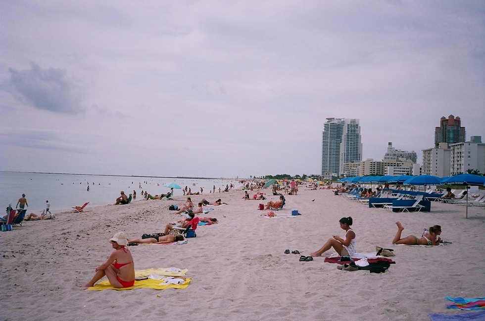 A view of people lying on Miami's South Beach with downtown Miami in the background