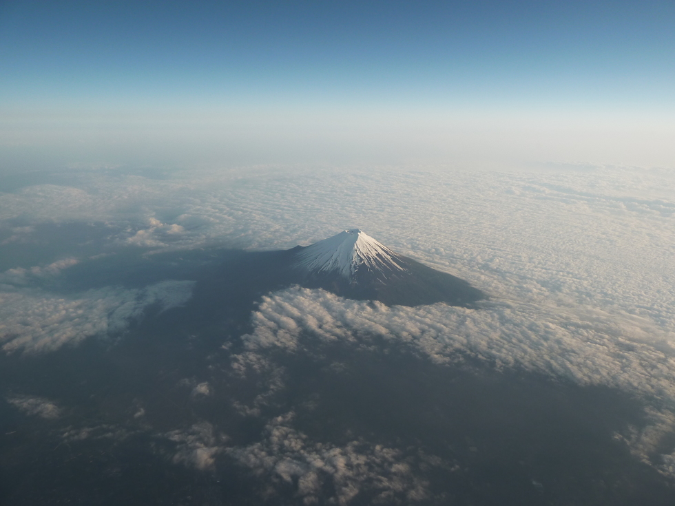 View of Mount Fuji's white capped peak with surrounding clouds. 