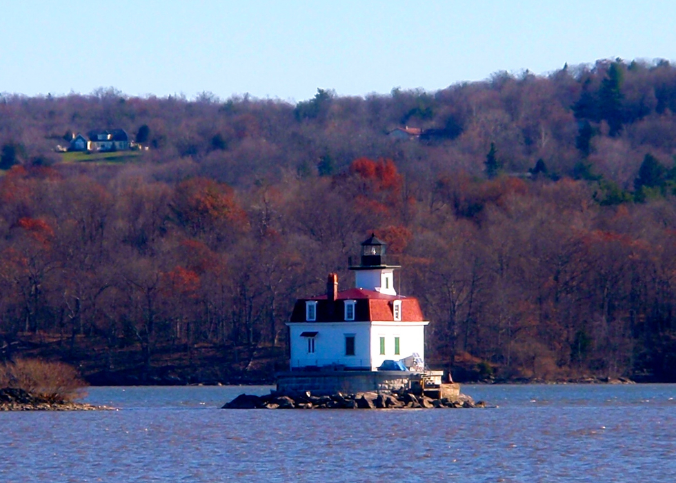 Lighthouse on Island in middle of Hudson River with a fall foliage in the background