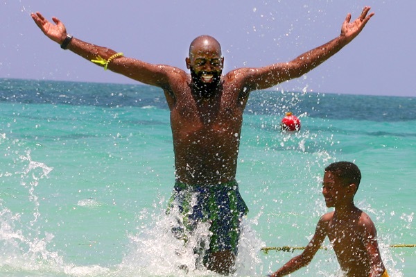 A man splashes in the ocean with his son in Jamaica.