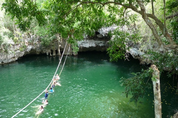 Zipliners dangle over the water at Selvática near Puerto Morelos