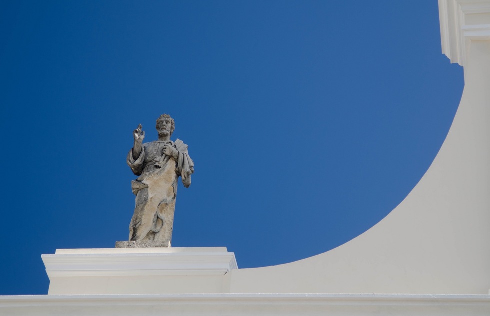 A statue on top of the San Juan Catedral, sillhoueted against the sky.