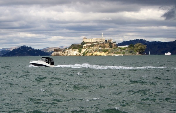 A boat zooms in front of Alcatraz Island.