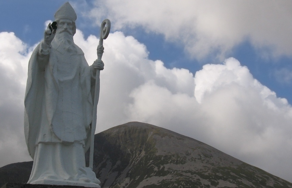 A statue of Saint Patrick stands in front of a mountain named after the saint in Ireland