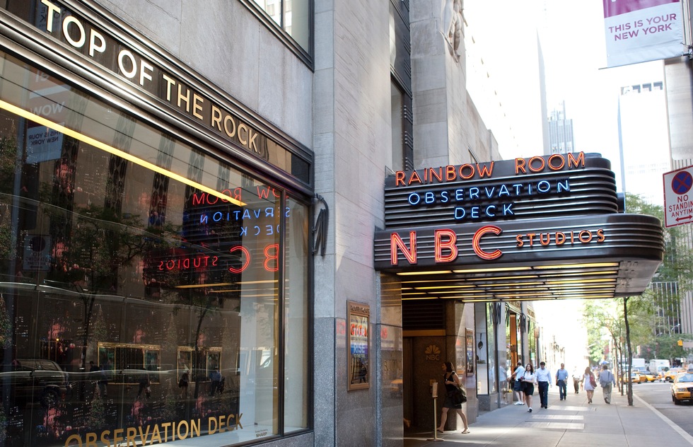 Exterior of Rockefeller Center, showing neon signs for NBC Studios, the Rainbow Room, and the Observation Deck