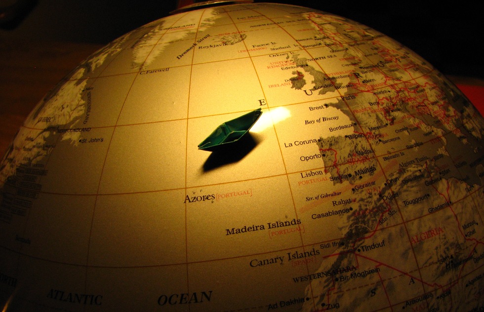A globe with a small paper boat on it.