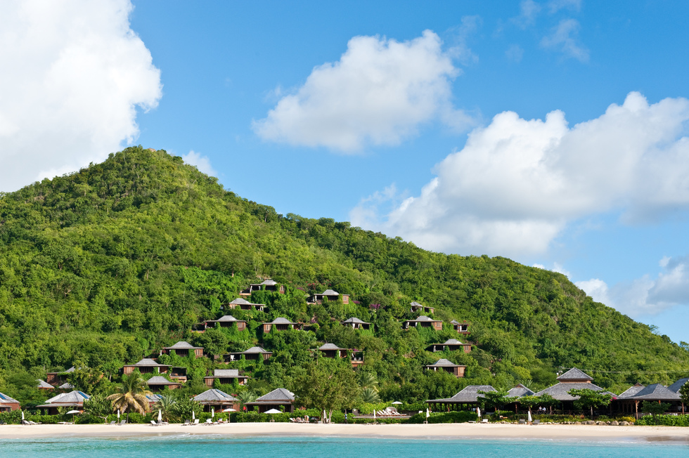 27 wooden suites on a verdant hillside are facing a white-sand beach and turquoise water.