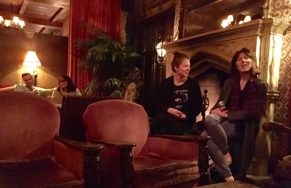Two guests chat in front of the fireplace at the bar of the Bowery Hotel