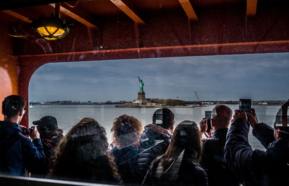 Tourists aboard the Staten Island Ferry take photos of the Statue of Liberty