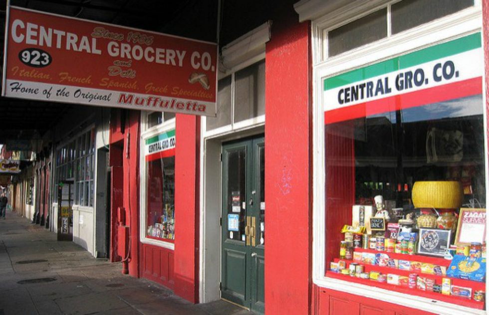 A red sign for Central Grocery hangs over the old store's front. Under the store name, the sign advertises the legendary muffuletta. 