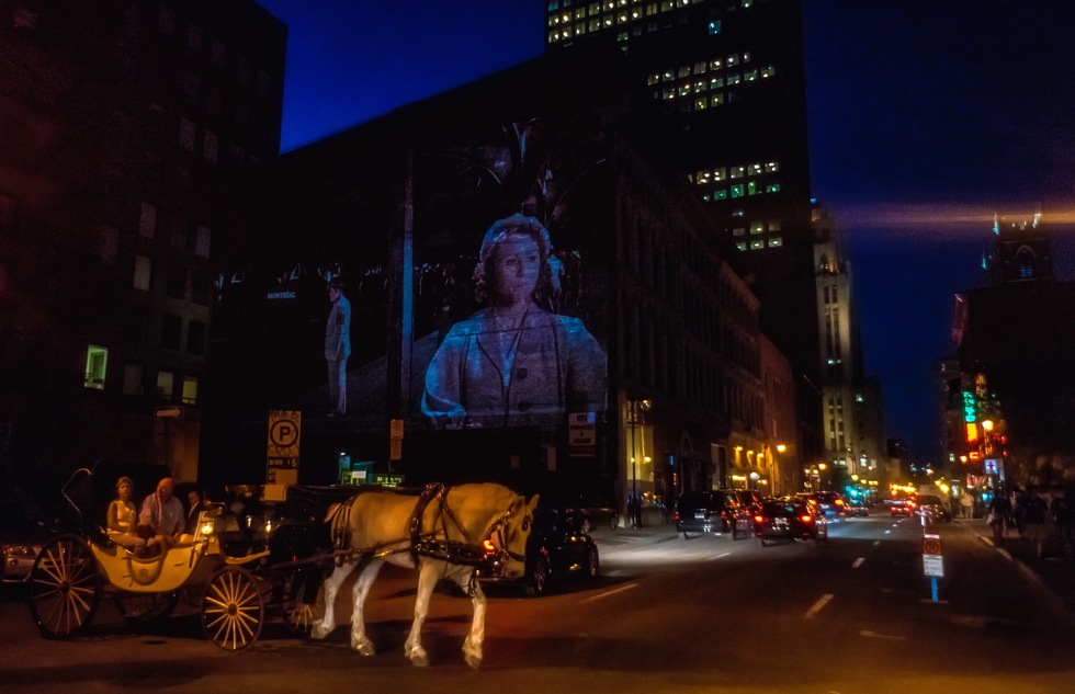 A horse and carriage pass a personal sound-and-light show happening on the streets of Old Montreal.