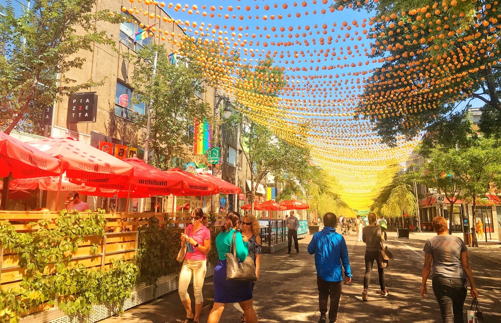 People stroll along St. Catharine Street, which is overhung by a canopy of colorful balls