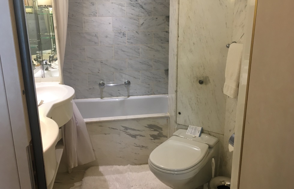 One small bathroom is set next to the entry door of each suite. It is clad in marble and features a double sink and a shower (but no bathtub).
