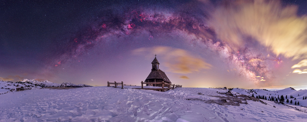 Wooden chapel amid snow and the Milky Way in Velika Planina, Slovenia