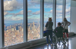 Three visitors look at the cityscape from One World Observatory.