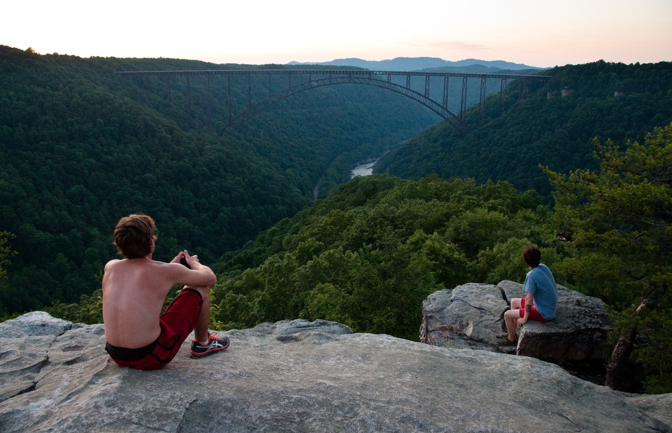 Great National Parks for Spring Vacations: Two boys sit at a high point, overlooking New River Gorge National Park in West Virginia.