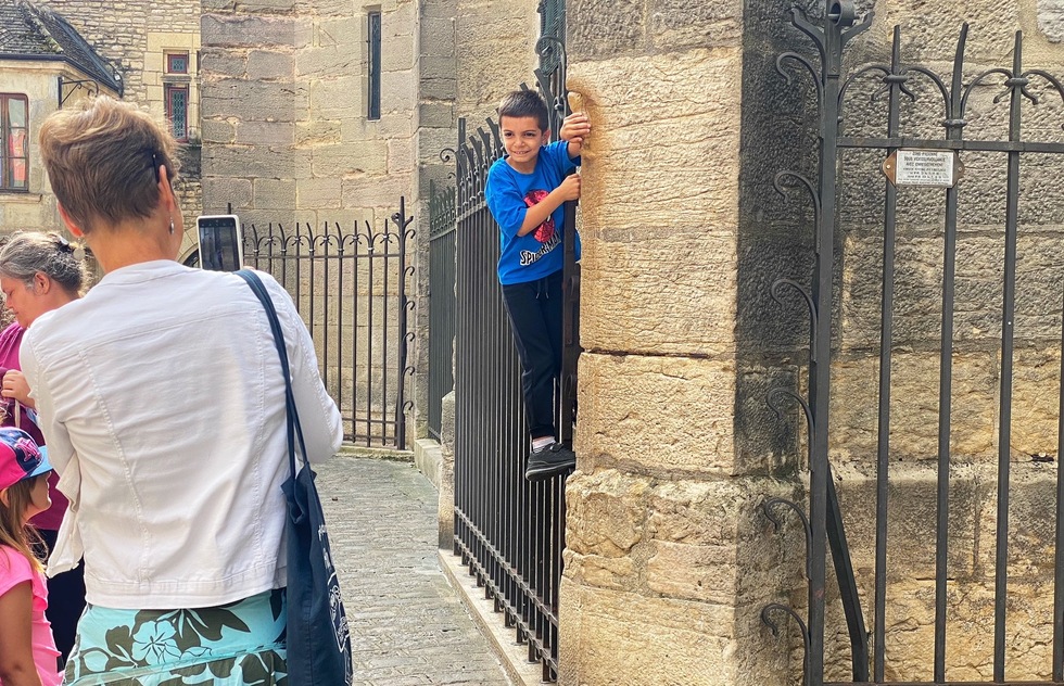 A young boy rubs the owl gargoyle on the side of Notre Dame de Dijon and makes a wish.