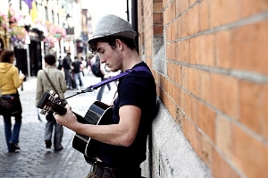 A street musician strums for tourists strolling Temple Bar's lively cobblestone streets.