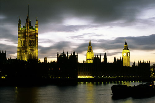 The Houses of Parliament buildings bathed in a yellow glow as evening falls over the city.