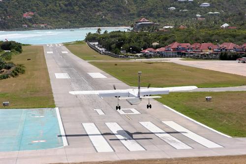 Small plane landing on the airstrip at the base of a steep hill on Saint Bathelemy Island, (St Barts)
