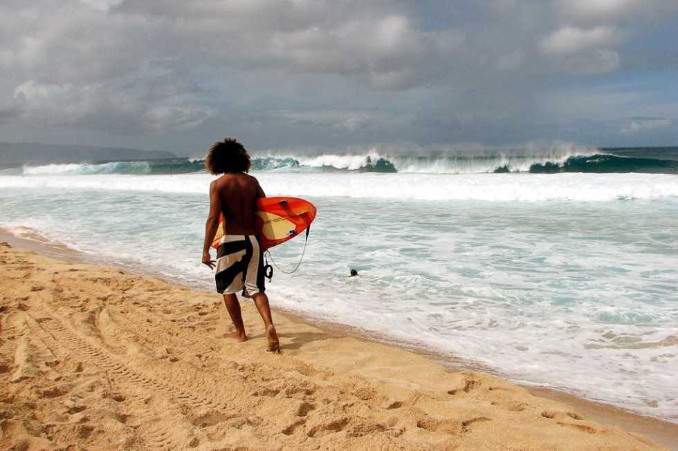 A surfer walking along Oahu, Hawaii's North Shore.