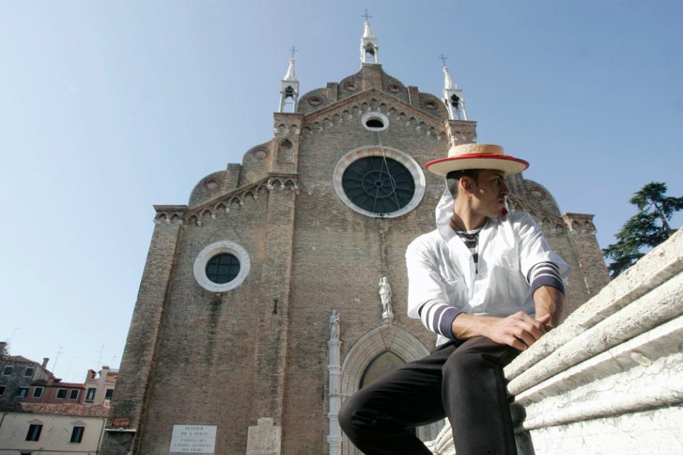 A gondolier sits down in front of the Basilica Santa Maria Gloriosa dei Frari, Venice.