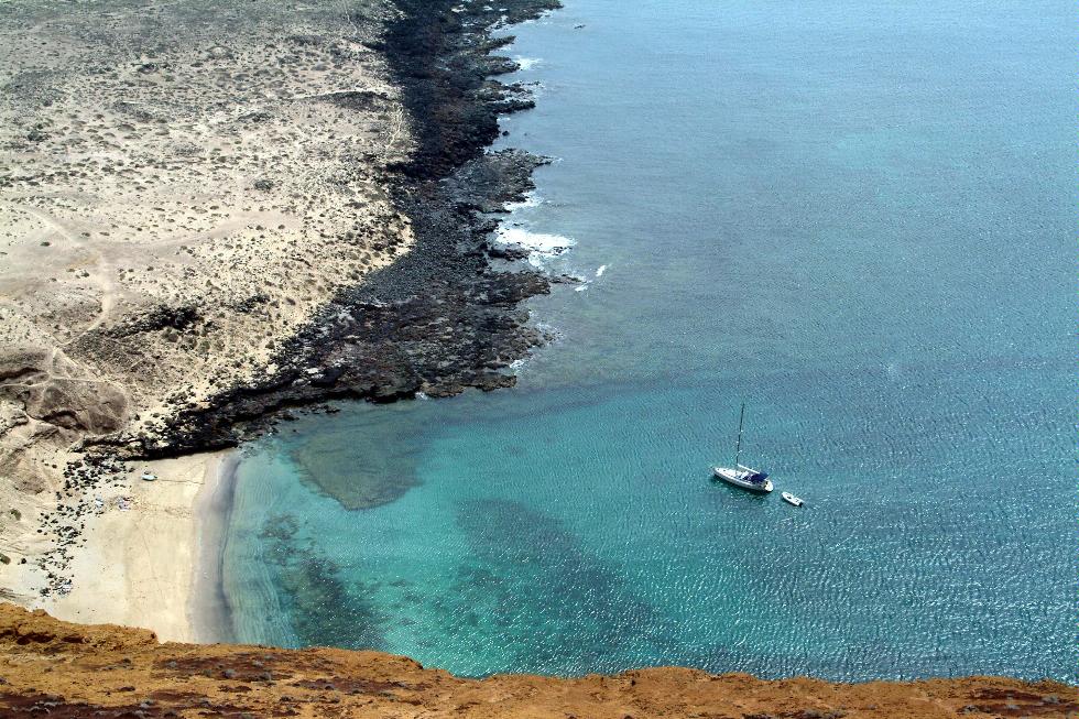 A yacht sails near a cove on Lanzarote, Canary Islands.