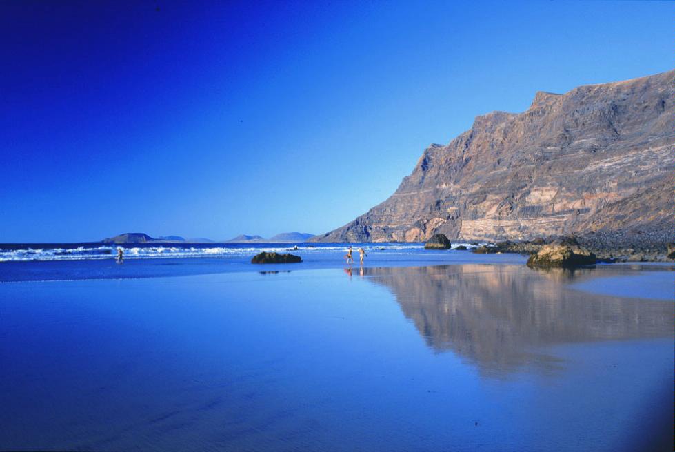 Two distant figures run on Playa de Famara, Lanzarote, Canary Islands.